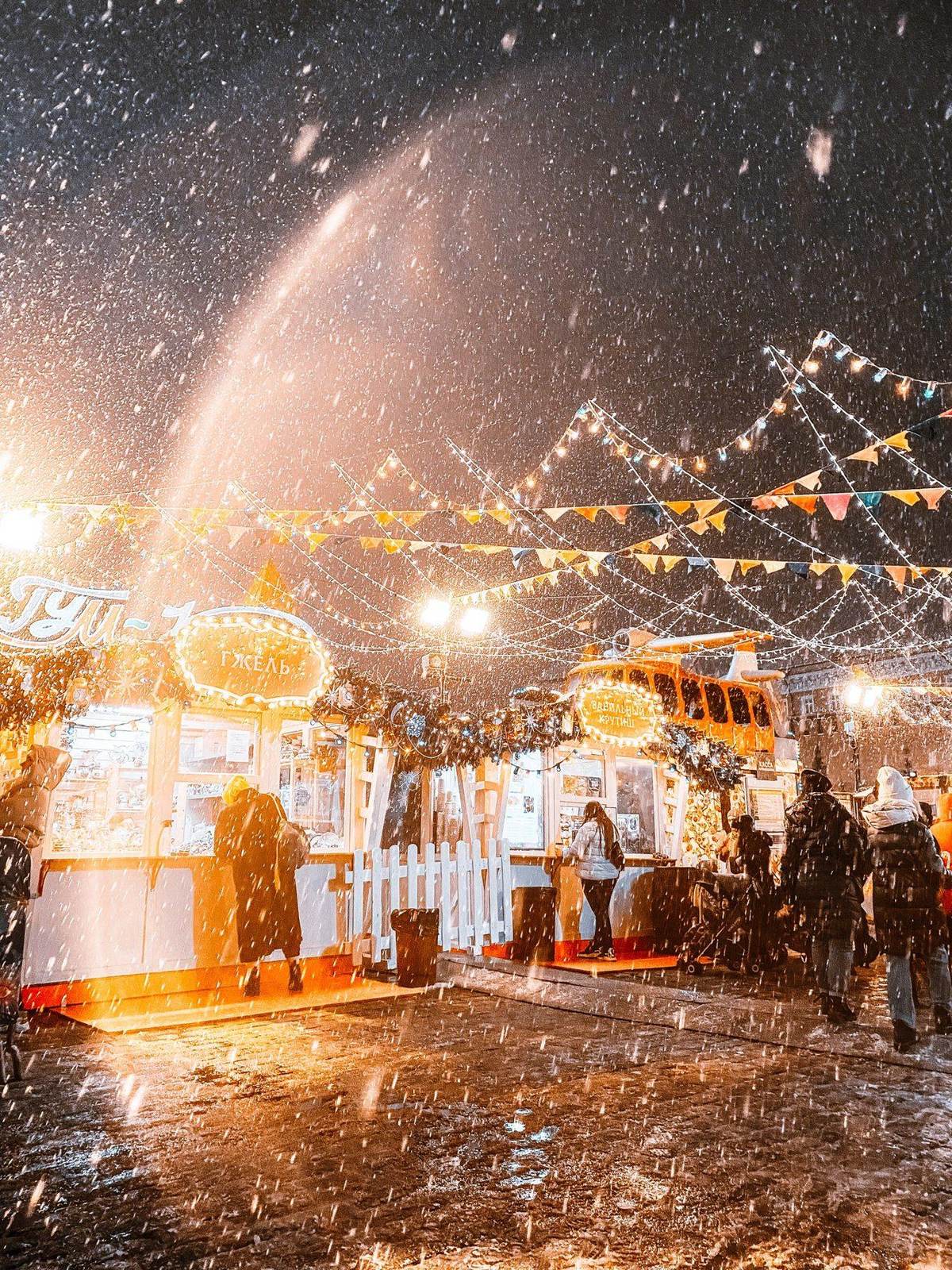 Beleuchteter Weihnachtsmarkt bei Schneefall