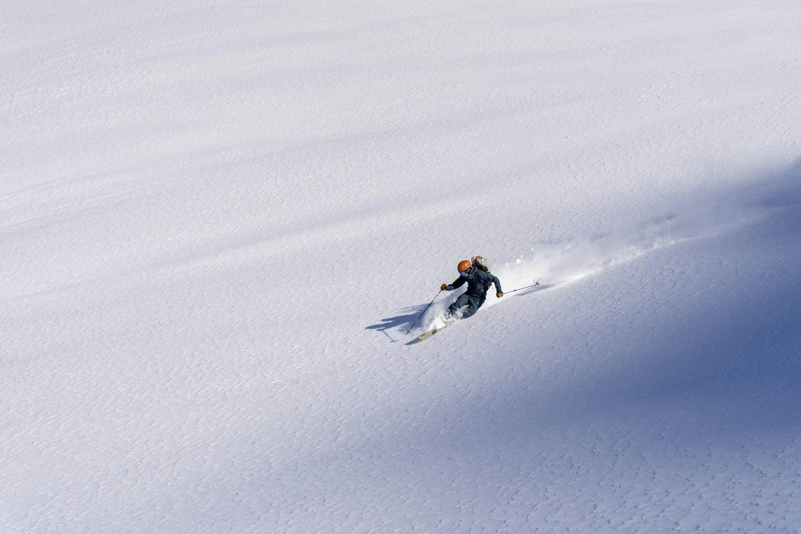 Ein einzelner Skifahrer in einem weiten unberührten Pulverhang