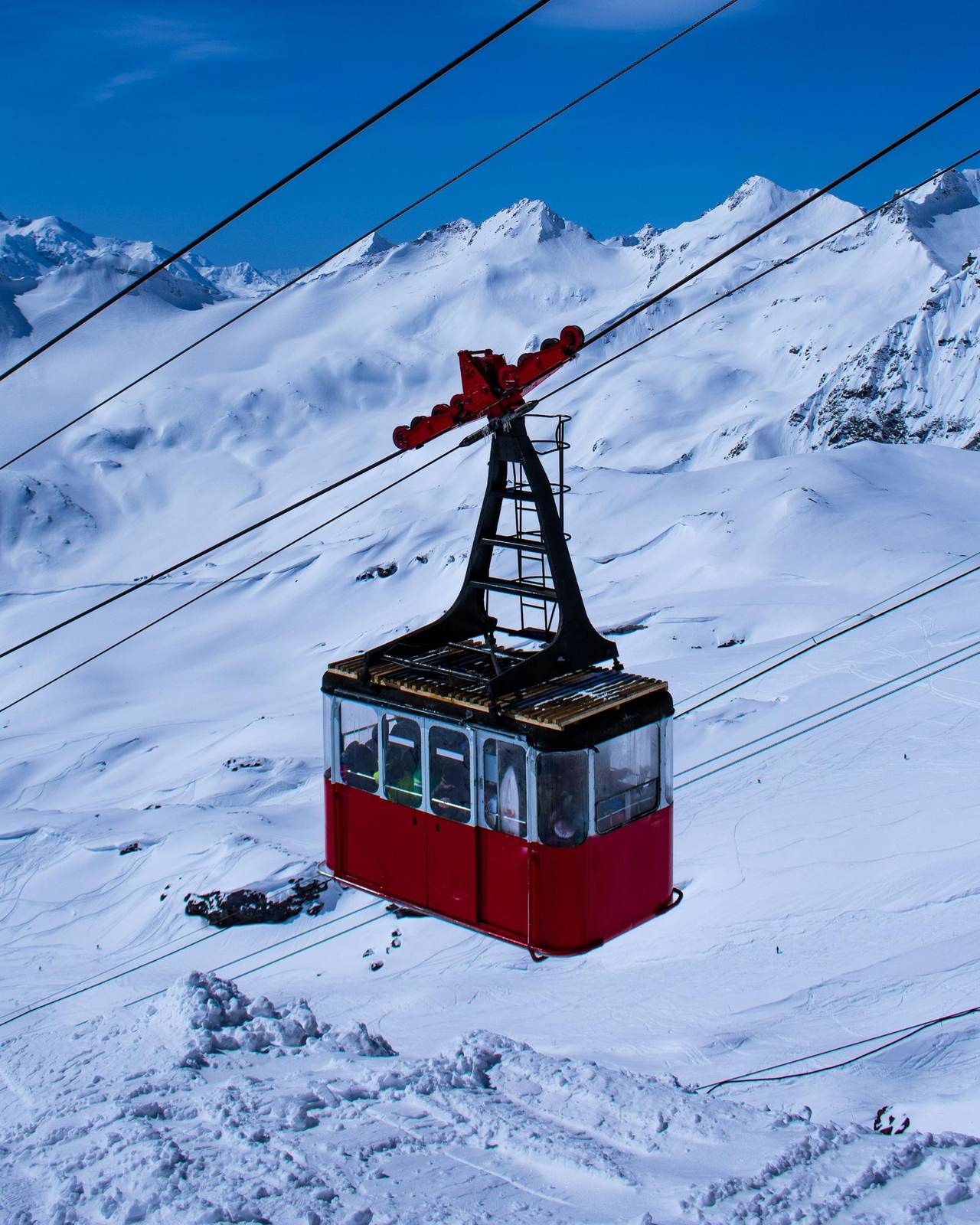 Eine rote Luftseilbahn schwebt über verschneiten Hängen